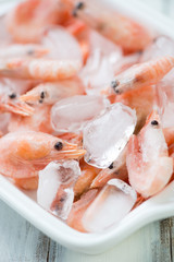 Close-up of raw iced shrimps, vertical shot