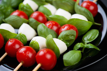 Kebabs with mozzarella, red tomatoes and basil leaves, close-up