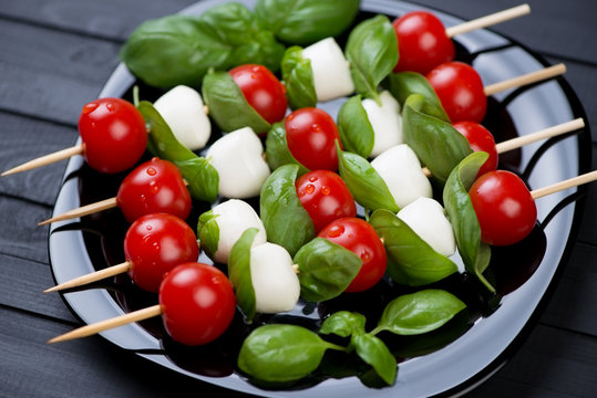 Kebabs with mozzarella balls, red tomatoes and green basil