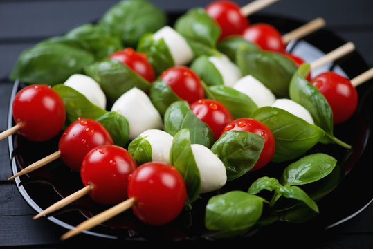 Kebabs with cherry tomatoes, mozzarella balls and green basil