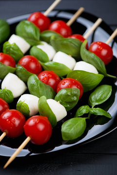 Red tomatoes, mozzarella and basil on skewers, vertical shot