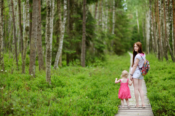 Naklejka na ściany i meble Cute toddler girl and her mother outdoors