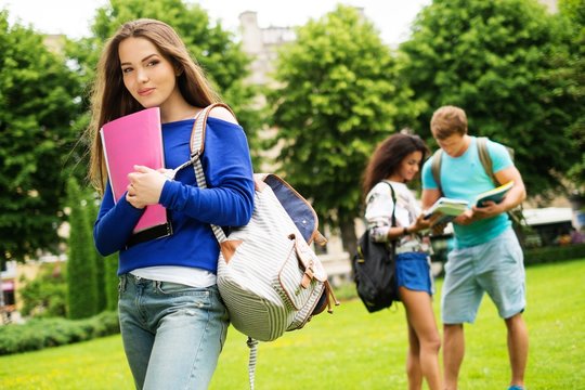 Beautiful young girl student in a city park on summer day