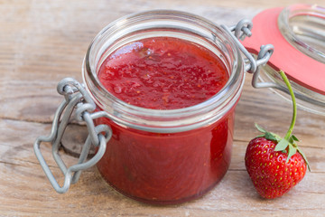 Erdbeermarmelade in einem Einmachglas auf Holz