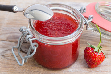 Erdbeermarmelade in einem Einmachglas auf Holz