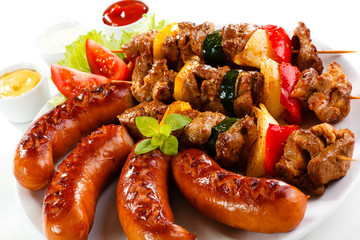 Grilled meat, sausages and vegetables on white background