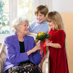 Children giving grandmother flowers.