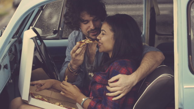 Couple eating pizza in retro car