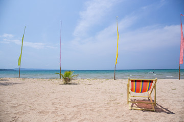 Beach chairs on the white sand beach with cloudy blue sky