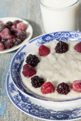 Breakfast porridge with frozen raspberries and blackberries.