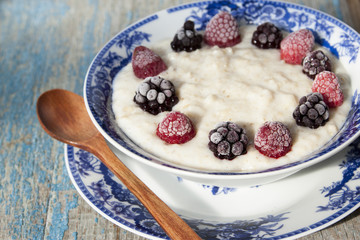 Breakfast porridge with frozen raspberries and blackberries.
