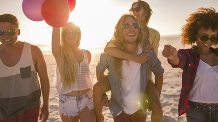 Friends dancing with balloons on beach - Powered by Adobe