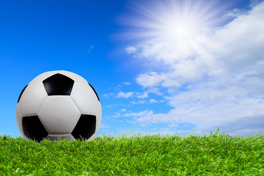 Soccer ball on grass with blue sky