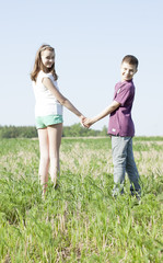 Boy holding girl's hand on green field