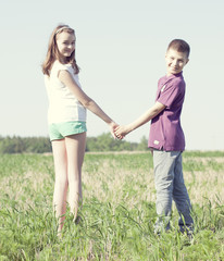 Boy holding girl's hand on green field