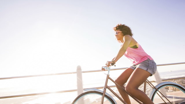 Hipster woman riding a bike near coast