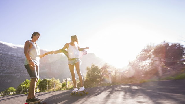 Friends longboard skating on road sunset