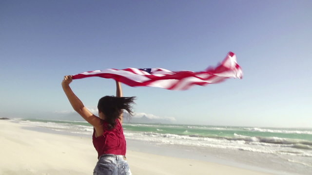 Girl waving american flag on beach