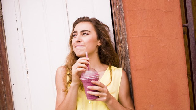 Woman with smoothie leaning in doorway