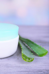 Cream and fresh green aloe leaves on wooden table