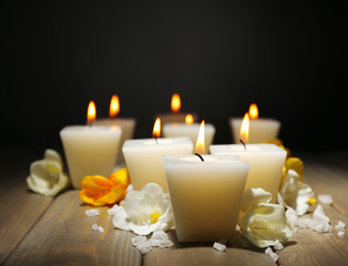 Beautiful candles with flowers on wooden background