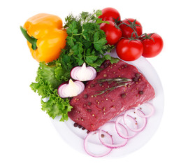 Raw beef meat with vegetables on plate isolated on white