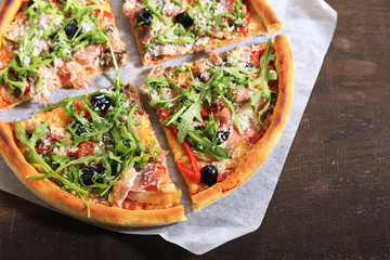 Pizza with arugula on color wooden background
