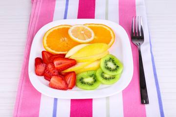 Various sliced fruits on plate on napkin close-up