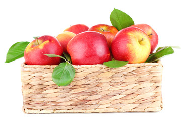 Ripe sweet apples with leaves in wicker crate, isolated on