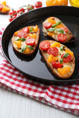 Tasty bruschetta with tomatoes in pan, on table