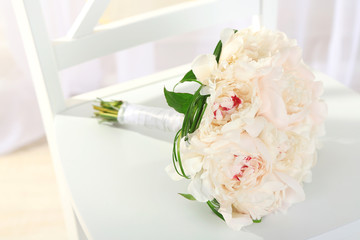 Beautiful wedding bouquet on chair on light background