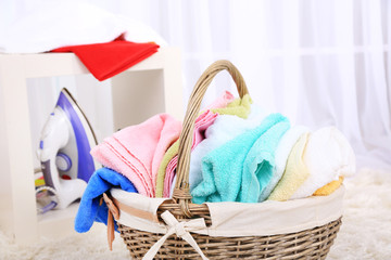 Colorful towels in basket on home interior background