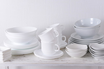 Set of white dishes on table on light background