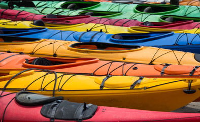 Large amount of colourful canoes outside.