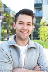 Hispanic guy in a grey jacket with crossed arms outside