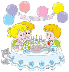 Little girls and boy at the table with a birthday cake