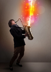Young man playing on saxophone with colorful sound waves