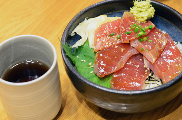 Raw tuna on rice in black bowl