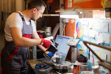Serviceman mixing paint in a car body workshop