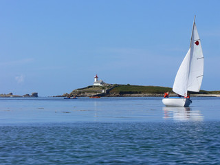 Voilier et kayaks sur la mer devant une île