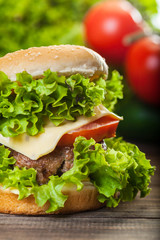 Cheeseburger with lettuce, onions and tomato in a sesame bun