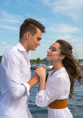 Guy holding hands a girl on a wooden pier near the water.