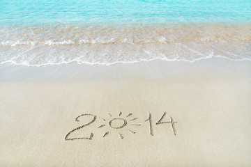 inscription 2014 on sea sand beach with the sun rays