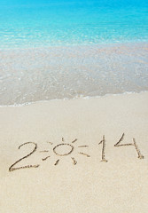 inscription 2014 on sea sand beach with the sun rays