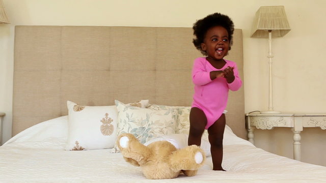 Cute baby girl playing and clapping on bed