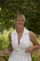 Portrait of a woman in a summer dress leaning on a fence