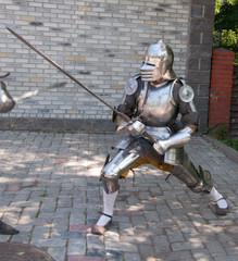 knight in the ancient metal armor standing near the stone wall