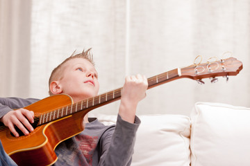 little boy playing guitar at home