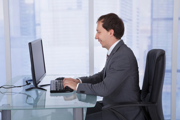 Fototapeta na wymiar Businessman Working On Computer At Desk In Office