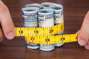 Hands Holding Banknote With Measure Tape